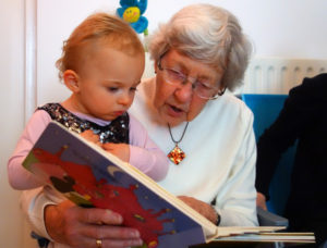 A grandmother and grandchild reading together.