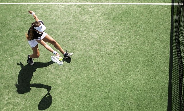 A tennis player returning a shot near to the net.